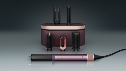 The Dyson Airwrap Co-anda2x multi-styler and dryer with the Airsmooth attachment next to a blonde model.