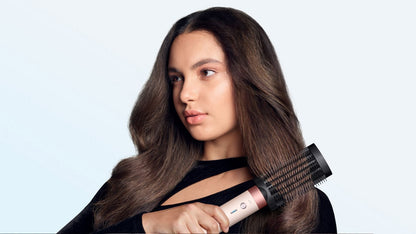 Model brushes her hair with the Dyson Anti-snag loop brush 2x.