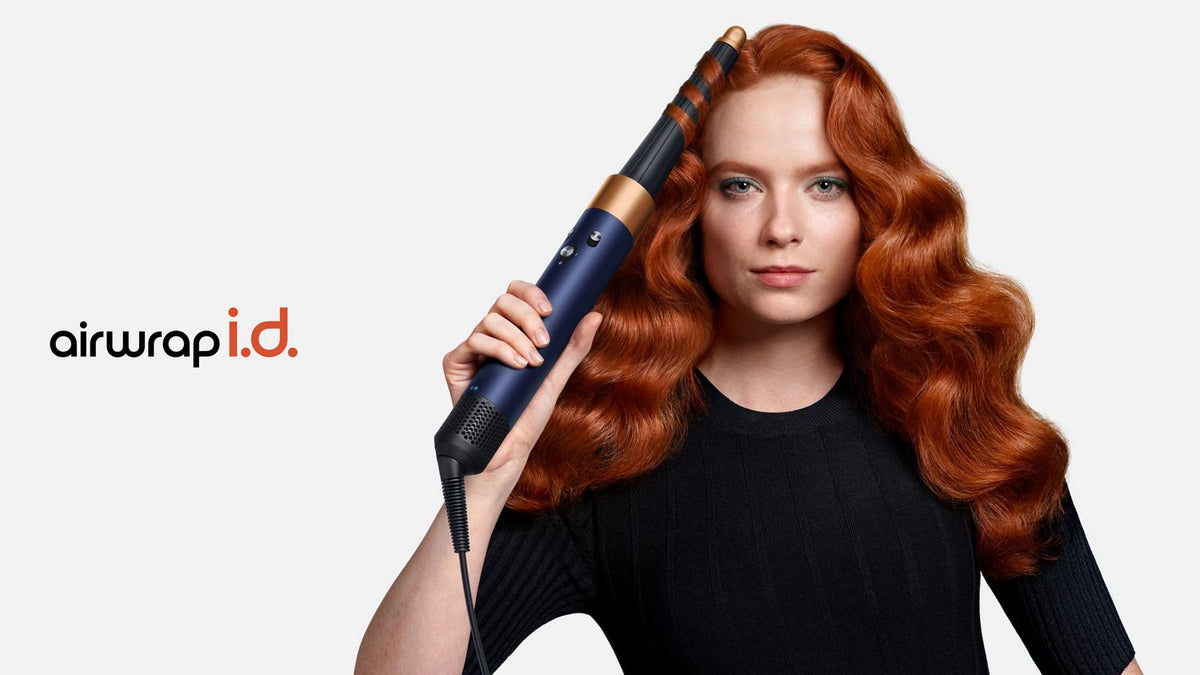 A redhead model adds waves to her hair using the Dyson Airwrap i.d. multi-styler and dryer.