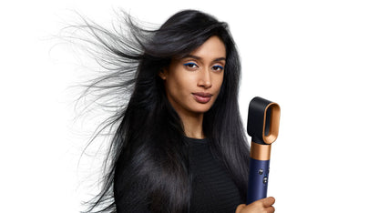 A redhead model curls her hair using the Dyson Airwrap i.d. multi-styler and dryer.