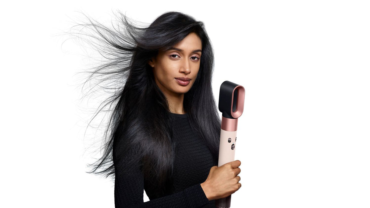 Model holding the Dyson Airwrap ID multi-styler and dryer with the Fast dryer attachment.