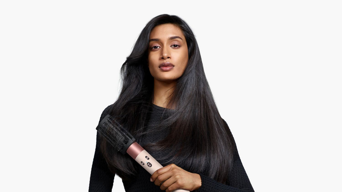 Model holding the Dyson Airwrap ID multi-styler and dryer with the Anti-tangle loop brush.